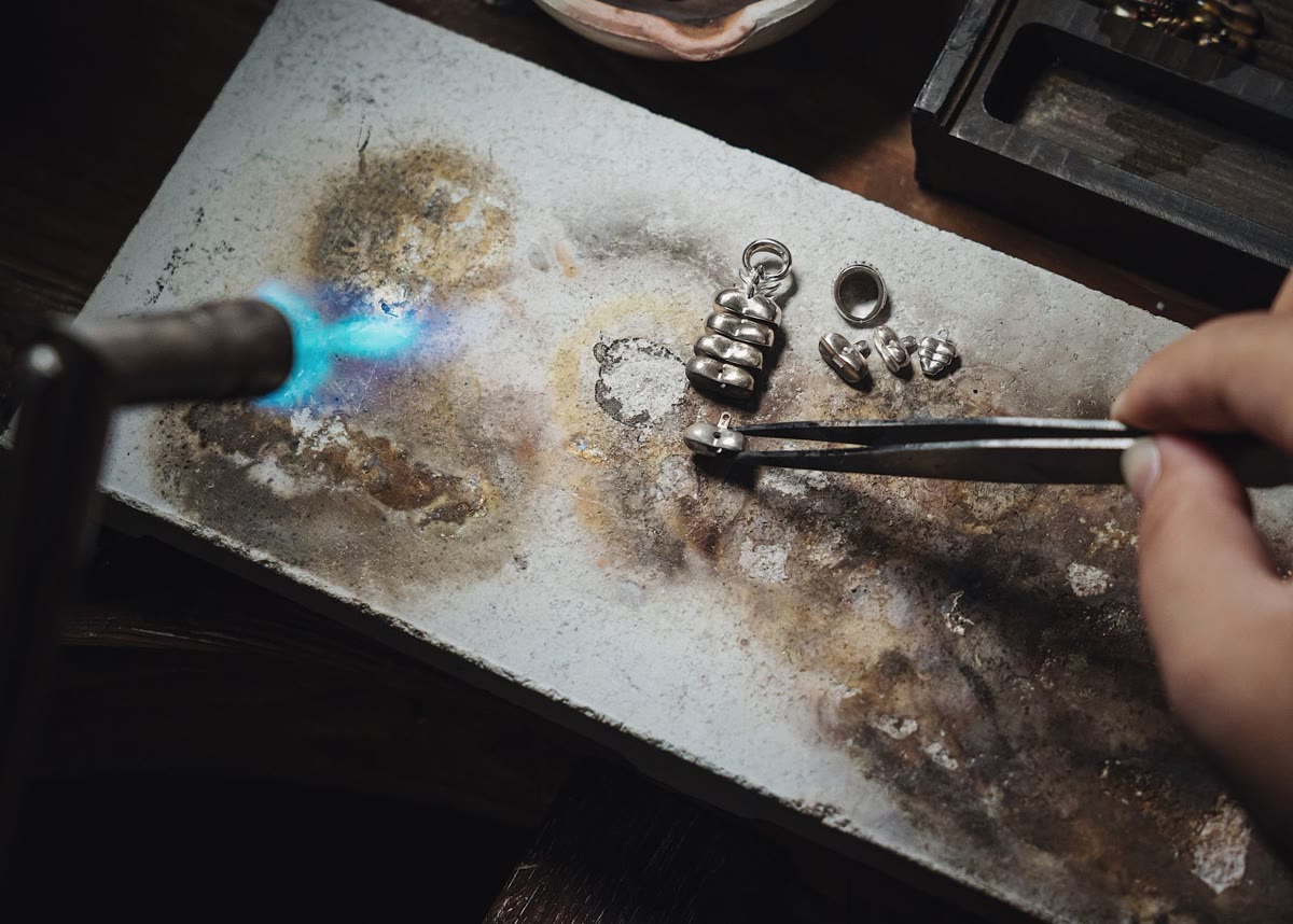 Clasps and jump rings being torch-soldered together during jewellery assembly